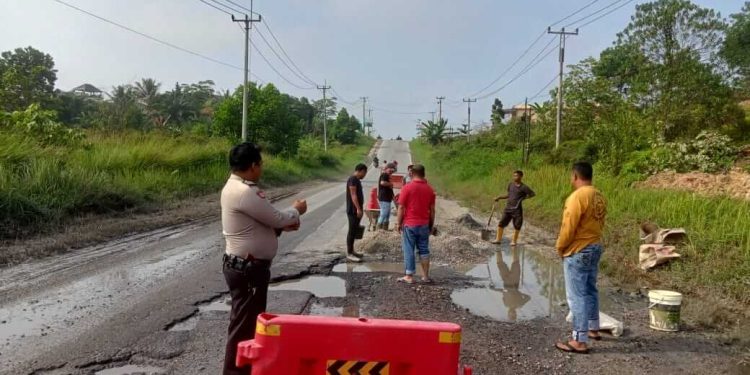 Polsek Kerinci Kanan melakukan semenisasi jalan berlobang di depan Mako Polsek Kerinci Kanan.